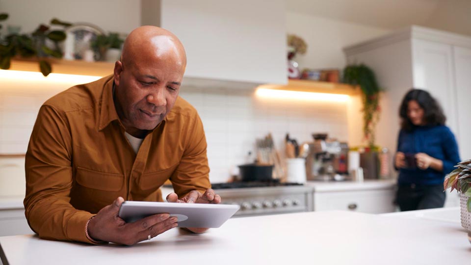 Older African make with bald head using a tablet